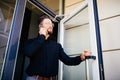 Business man holding the office door and get outdoor white speak on phone. Man get out exit from office building Royalty Free Stock Photo