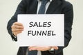 Business man holding Sales funnel TEXT on white sheet