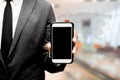 Business man holding smart phone with blur image of hall way Royalty Free Stock Photo