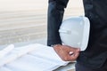 The business man holding the white safety helmet with blueprint Royalty Free Stock Photo