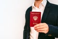 A business man in a jacket and shirt holds a Russian passport