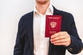 A business man in a jacket and shirt holds a Russian passport