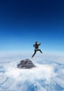 Business man jumping off mountain peak in the clouds Royalty Free Stock Photo