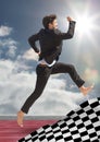 Business man jumping on track behind checkered flag and against sky with sun Royalty Free Stock Photo