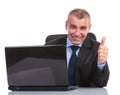 Business man at laptop, shows thumb up sign Royalty Free Stock Photo