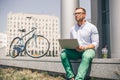 Business man with laptop and sport bike sitting in city. Royalty Free Stock Photo