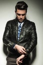 Business man in leather jacket, looking down while fixing his sleeve. Royalty Free Stock Photo