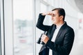 Business man looking with binoculars on competitors over panoramic windows Royalty Free Stock Photo