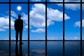 Business Man looking out of high rise office window at blue sky bright sunshine and white clouds. Royalty Free Stock Photo