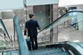 business man with luggage going down the escalator . Royalty Free Stock Photo