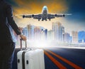 business man and luggage standing on airport runways with passenger jet plane flying above airport runway use for aircraft Royalty Free Stock Photo