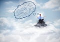 Business man meditating on mountain peak with blue thought cloud