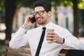Business man outdoors in the park talking by phone drinking coffee. Royalty Free Stock Photo