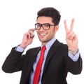 Business man on phone shows victory sign Royalty Free Stock Photo