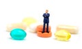 Business man on pills on white background. Miniature figurine of businessman macro photo