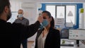 Business man with protective face mask checking collegues temperature