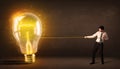 Business man pulling a big bright glowing light bulb Royalty Free Stock Photo