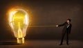 Business man pulling a big bright glowing light bulb Royalty Free Stock Photo