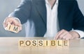 Business man puts away first two letters from the word impossible, so it becomes possible; management or solution finding concept