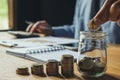 Business man putting coin in glass bottle saving bank and account for his money all in finance accounting concept. Royalty Free Stock Photo