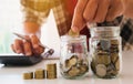 Business man putting coin in glass bottle saving bank and account for his money all in finance accounting concept. Royalty Free Stock Photo