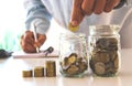 Business man putting coin in glass bottle saving bank and account for his money all in finance accounting concept. Royalty Free Stock Photo