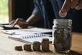 Business man putting coin in glass bottle saving bank and account for his money all in finance accounting concept. Royalty Free Stock Photo