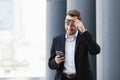 Business man raised his glasses to watch good news on phone, pleasant surprise Royalty Free Stock Photo