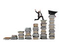 Business man reaches the graduation hat jumping on piles of books. Concept of success and determination on study