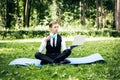 Business man relaxing in a park in the lotus position, he can`t relax in any way, in one hand holds a laptop in the other a cup of Royalty Free Stock Photo