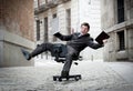 Business man rolling downhill on chair with computer and tablet Royalty Free Stock Photo