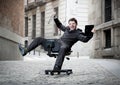 Business man rolling downhill on chair with computer and tablet Royalty Free Stock Photo