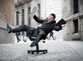 Business man rolling downhill on chair with computer and tablet Royalty Free Stock Photo