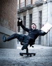 Business man rolling downhill on chair with computer and tablet