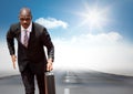 Business man running with briefcase on road against sky with sun Royalty Free Stock Photo