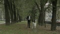 Business man running with playful big white dog in the green city park