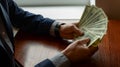 Business Man`s Hand To Holding Money. Handful Of Dollars On wood Background Royalty Free Stock Photo