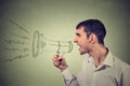 Business man shouting into a megaphone isolated on gray background