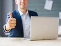 Business man showing a thumb up to a laptop on the office background. Digital technology concept. Royalty Free Stock Photo