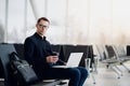 A business man sitting at the airport park working with his laptop and drinking takeaway coffee while waiting the flight Royalty Free Stock Photo