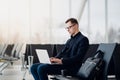 A business man sitting at the airport park working with his laptop and drinking takeaway coffee while waiting the flight Royalty Free Stock Photo