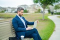 Business man sitting on a bench in park. Man is working on computer outside. Handsome business man making online work Royalty Free Stock Photo