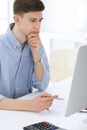 Business man sitting and working with computer and calculator in white office. Student guy studying at home or young Royalty Free Stock Photo