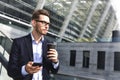 Business man stand at street holding a smartphone and coffee in office park Royalty Free Stock Photo
