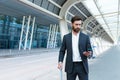 Business man standing background a modern train station airport or bus stop in formal suit with a suitcase using app mobile phone