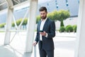 Business man standing background a modern train station airport or bus stop in formal suit with a suitcase using app mobile phone Royalty Free Stock Photo