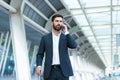 Business man standing background a modern train station airport hotel or bus stop in formal suit with a suitcase speaks mobile Royalty Free Stock Photo