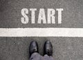 Business man standing on grunge concrete with white race line beginning idea. Top view. Feet and black shoes with word start Royalty Free Stock Photo