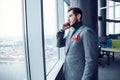 Mature business man standing inside office building and using cell phone. Man standing by window and talking on mobile Royalty Free Stock Photo