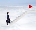 Business man stepping up on stairs to red flag with cloud and sk Royalty Free Stock Photo